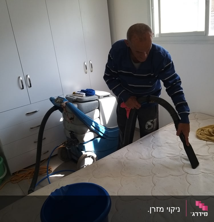 אדם מנקה מזרן עם שואב אבק תעשייתי